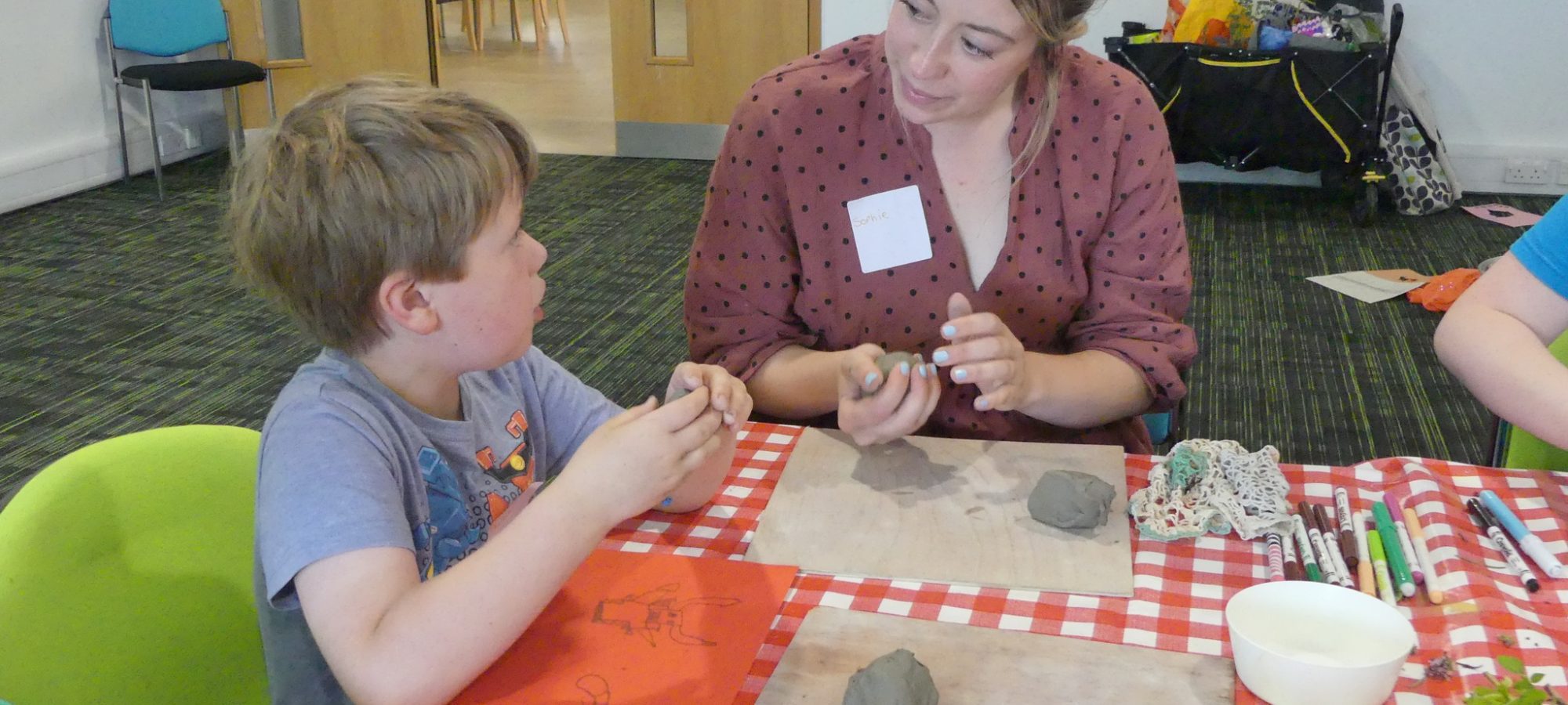 Workshop image with a facilitator and a young child making clay art