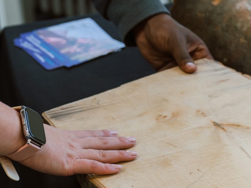 Two people's hands holding wood from the Sycamore Gap tree