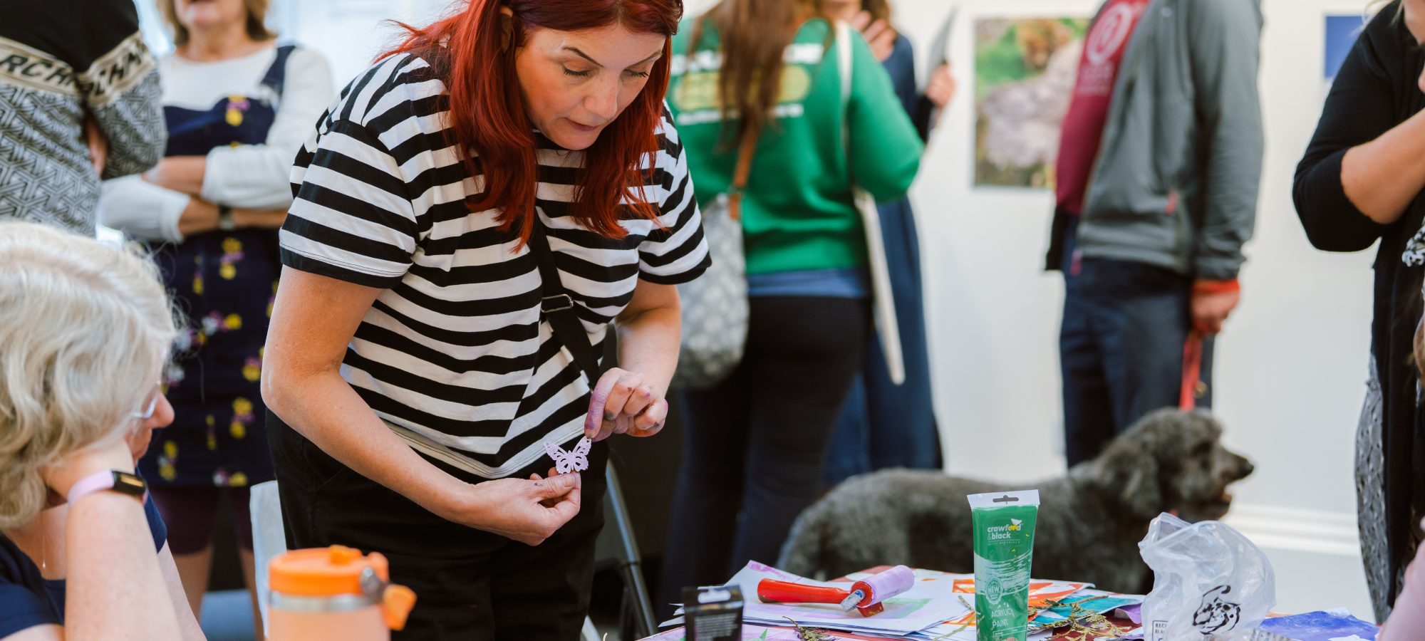 A busy Helix Arts HQ, with people at a table rolling ink on stencils.